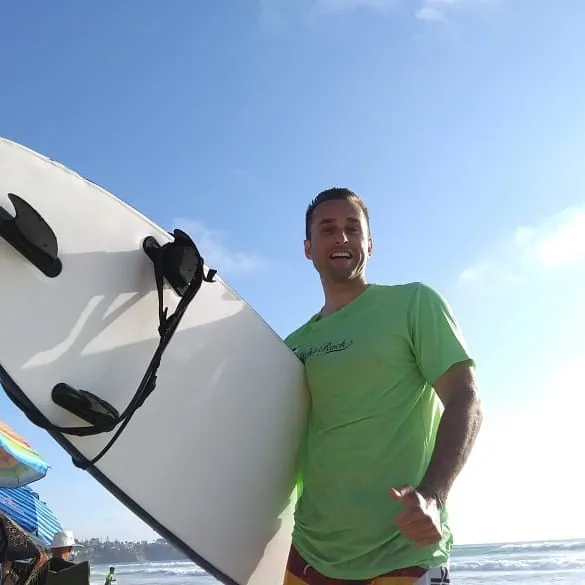 Josh on the beach holding a surfboard