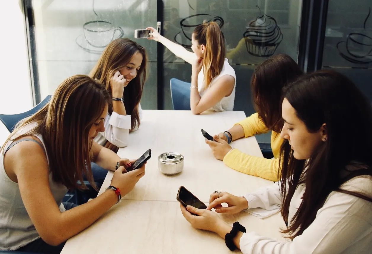 Friends at a table all looking at their phones