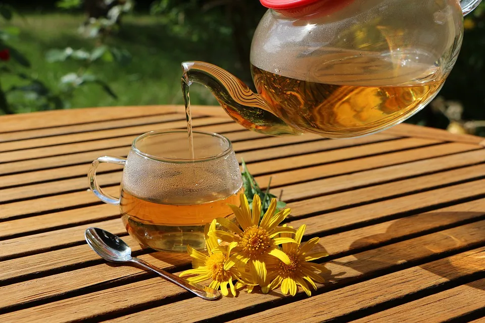 Herbal tea being poured from a glass teapot