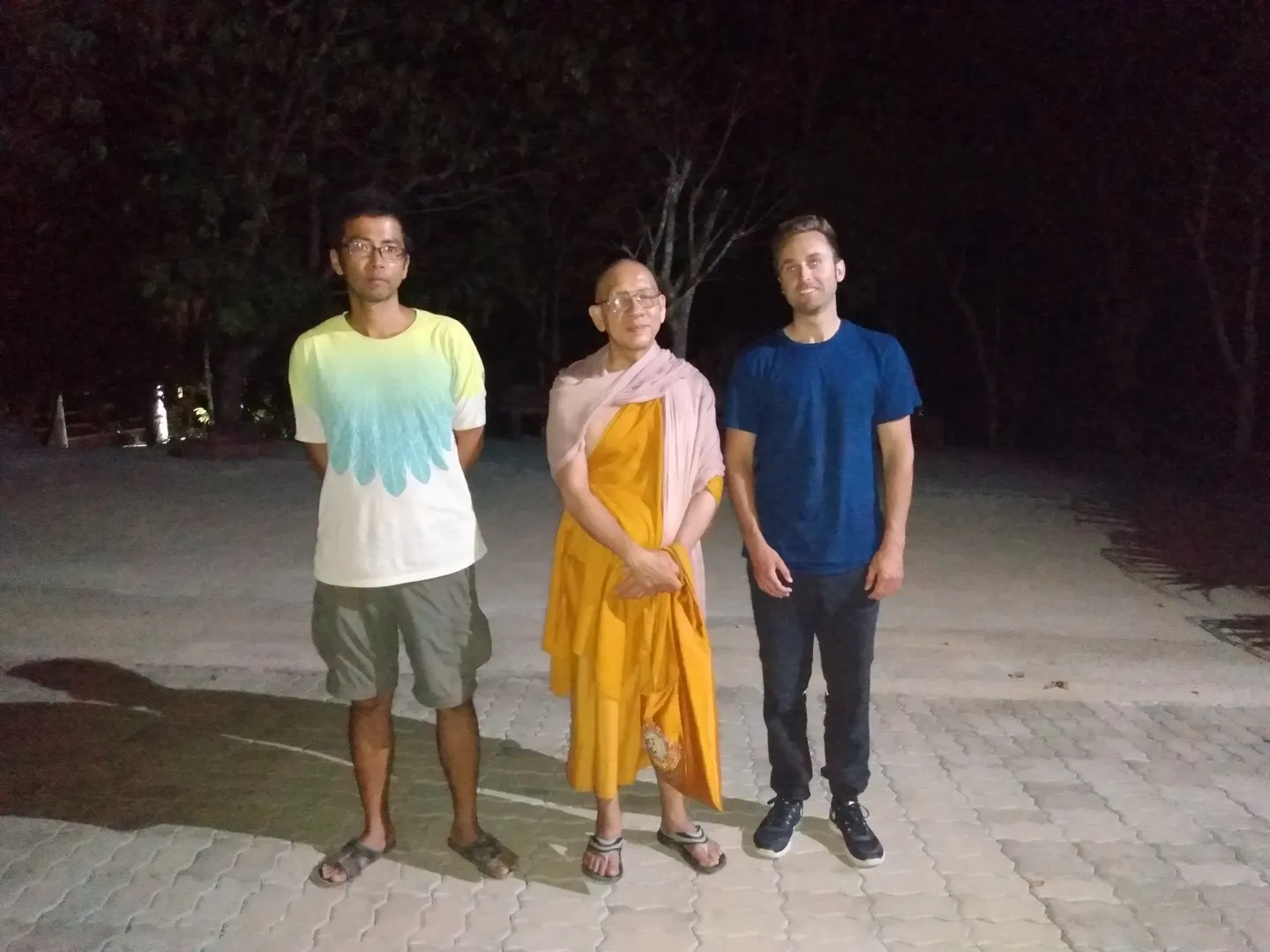 Three people standing together at the meditation center at night
