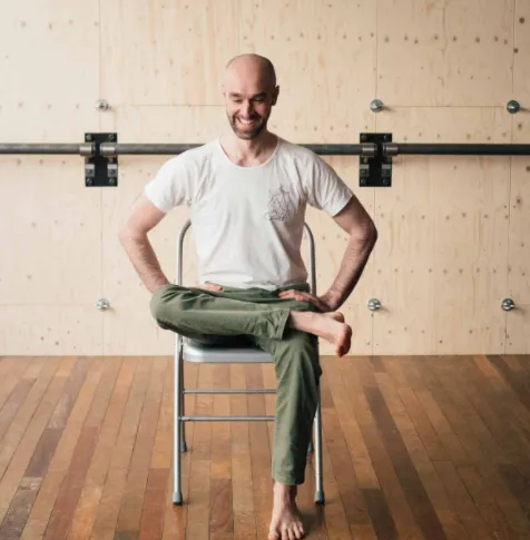 Man doing a seated pigeon stretch on a chair