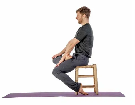 Man in thunderbolt pose on a stool