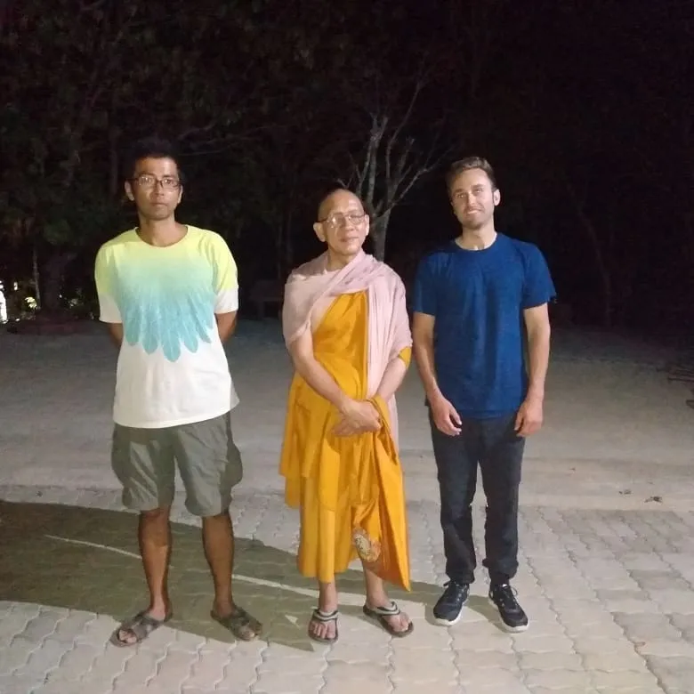 Three people standing together at the meditation center at night