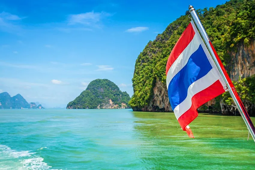 Thai flag on a boat near limestone islands in Thailand